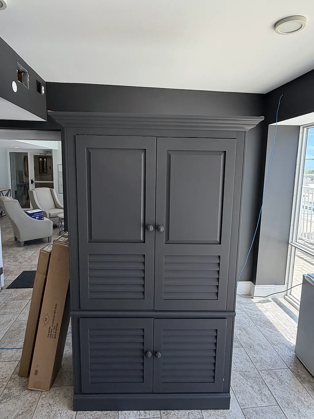 The same louvered built-in cabinet refinished in deep charcoal against charcoal walls and a white ceiling
