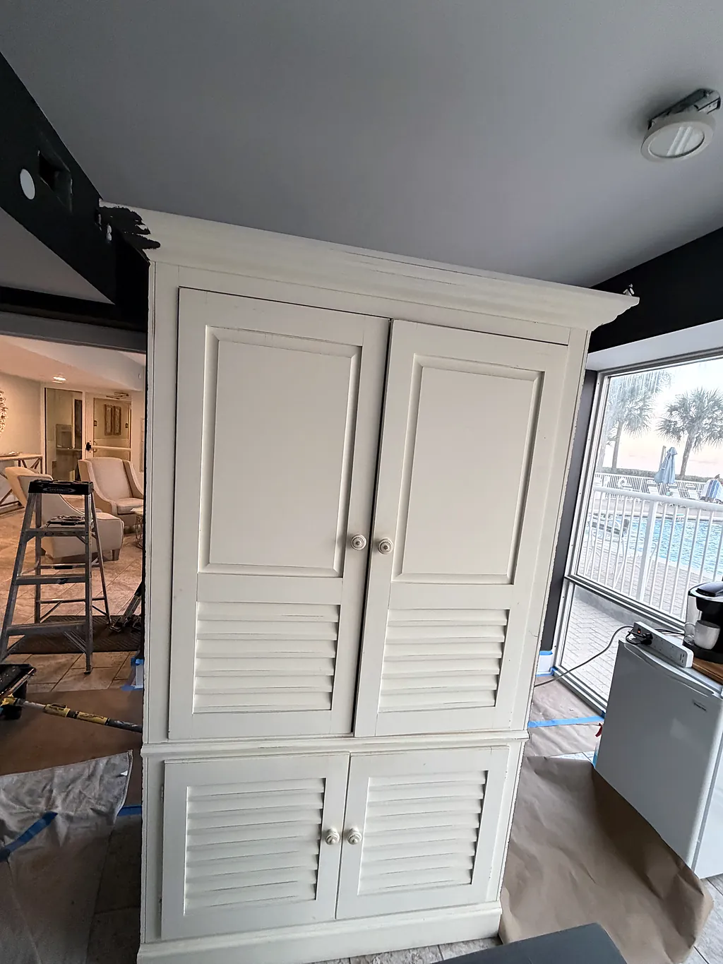 Cream louvered built-in cabinet in a Destin, Florida condo before being refinished