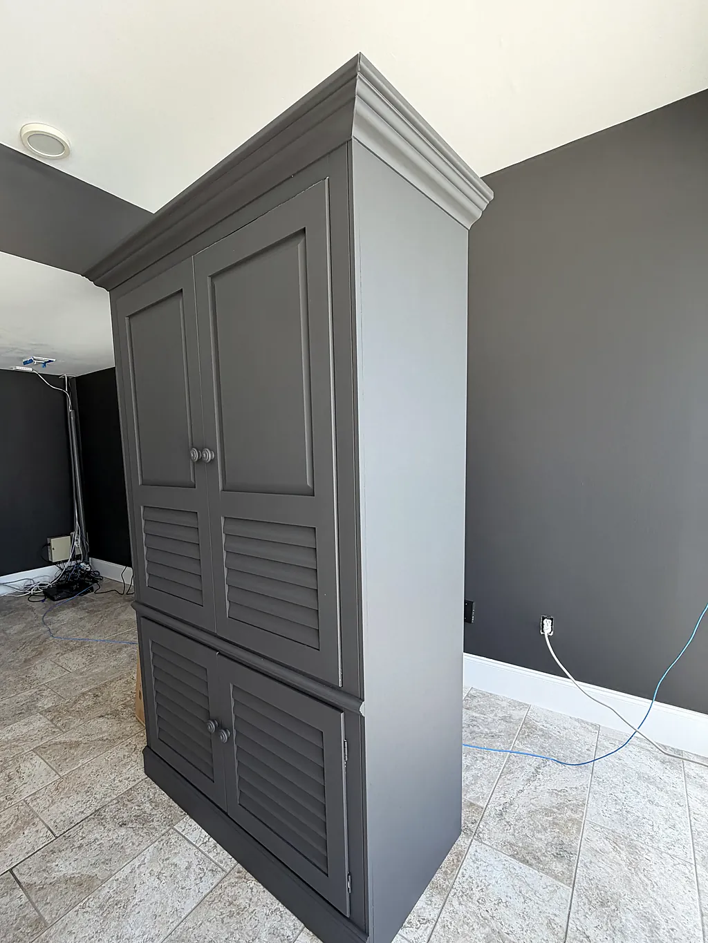 The finished charcoal cabinet and repainted walls seen from the same corner of the room