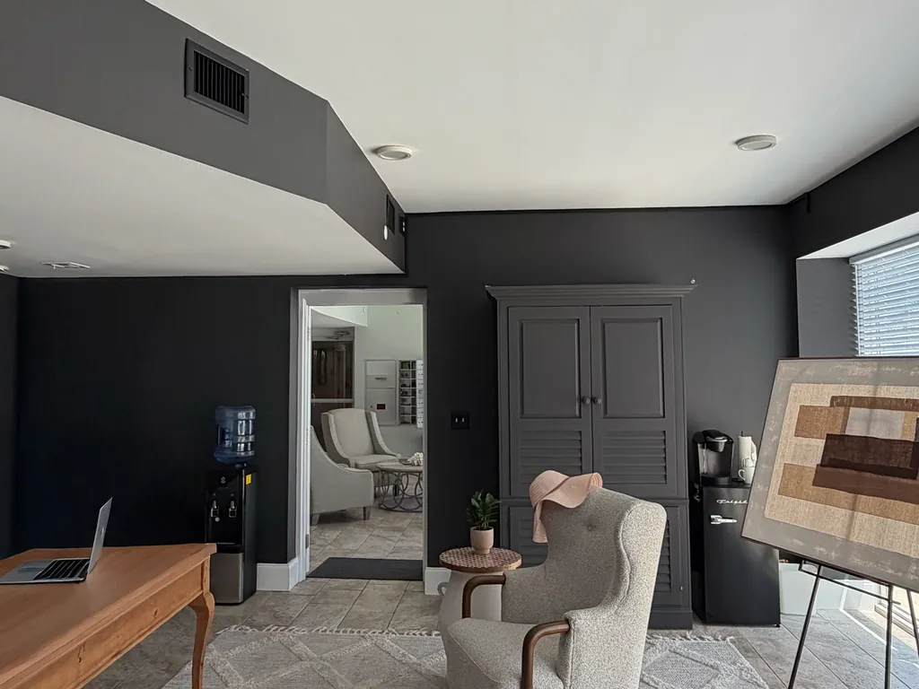 The same condo living room after repainting, with charcoal walls, a white ceiling and the built-in refinished in charcoal