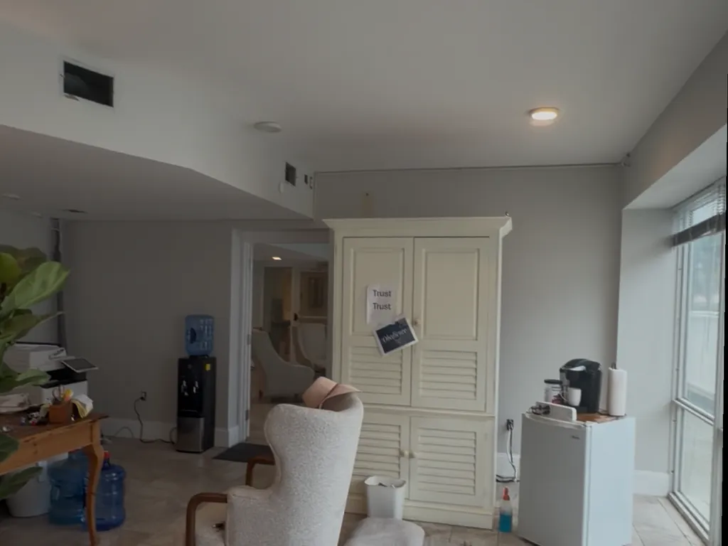Condo living room in Destin, Florida before repainting, with light gray walls and a cream louvered built-in