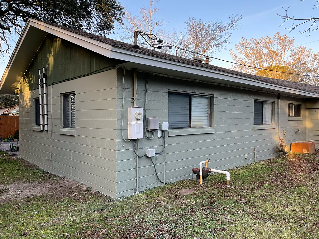 The same concrete block wall finished in sage green with a repainted gable and clean white fascia
