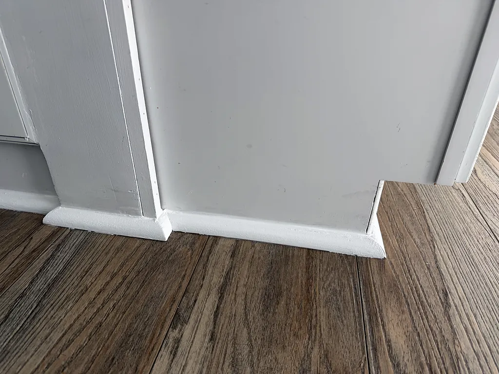 Close detail of painted door casing and baseboard meeting at a clean mitered corner