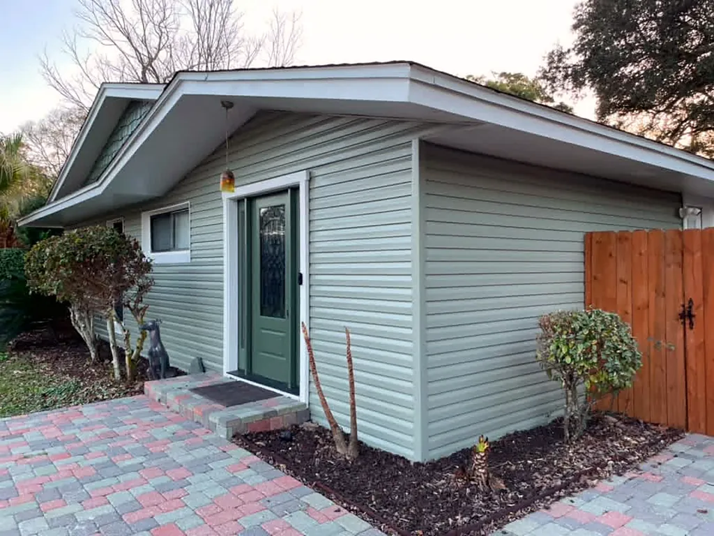 The same siding and entry finished in soft sage green with crisp white door trim